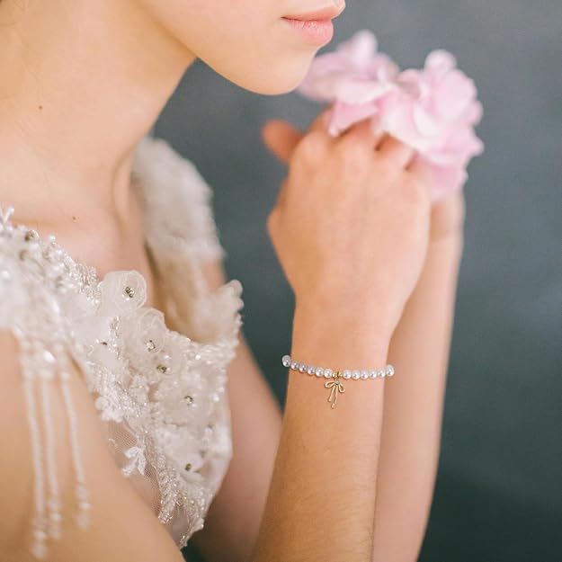 Pulsera de perlas delicadas con amuleto de lazo dorado